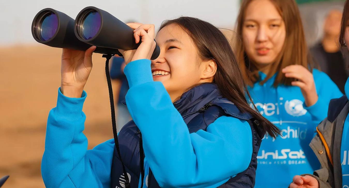 Girl looking through a binocular and smiling