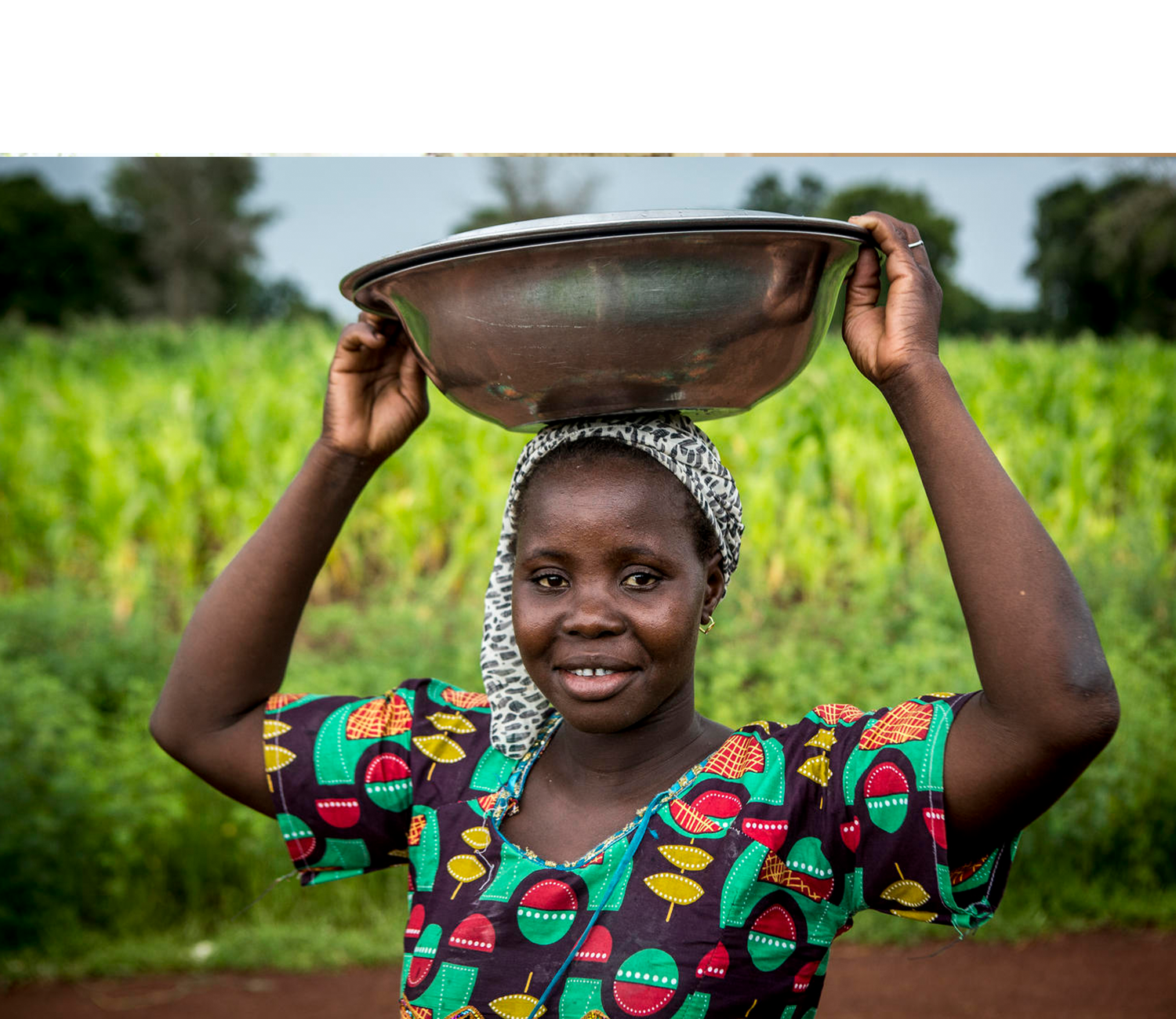 Smiling young work holding a metal dish on her head
