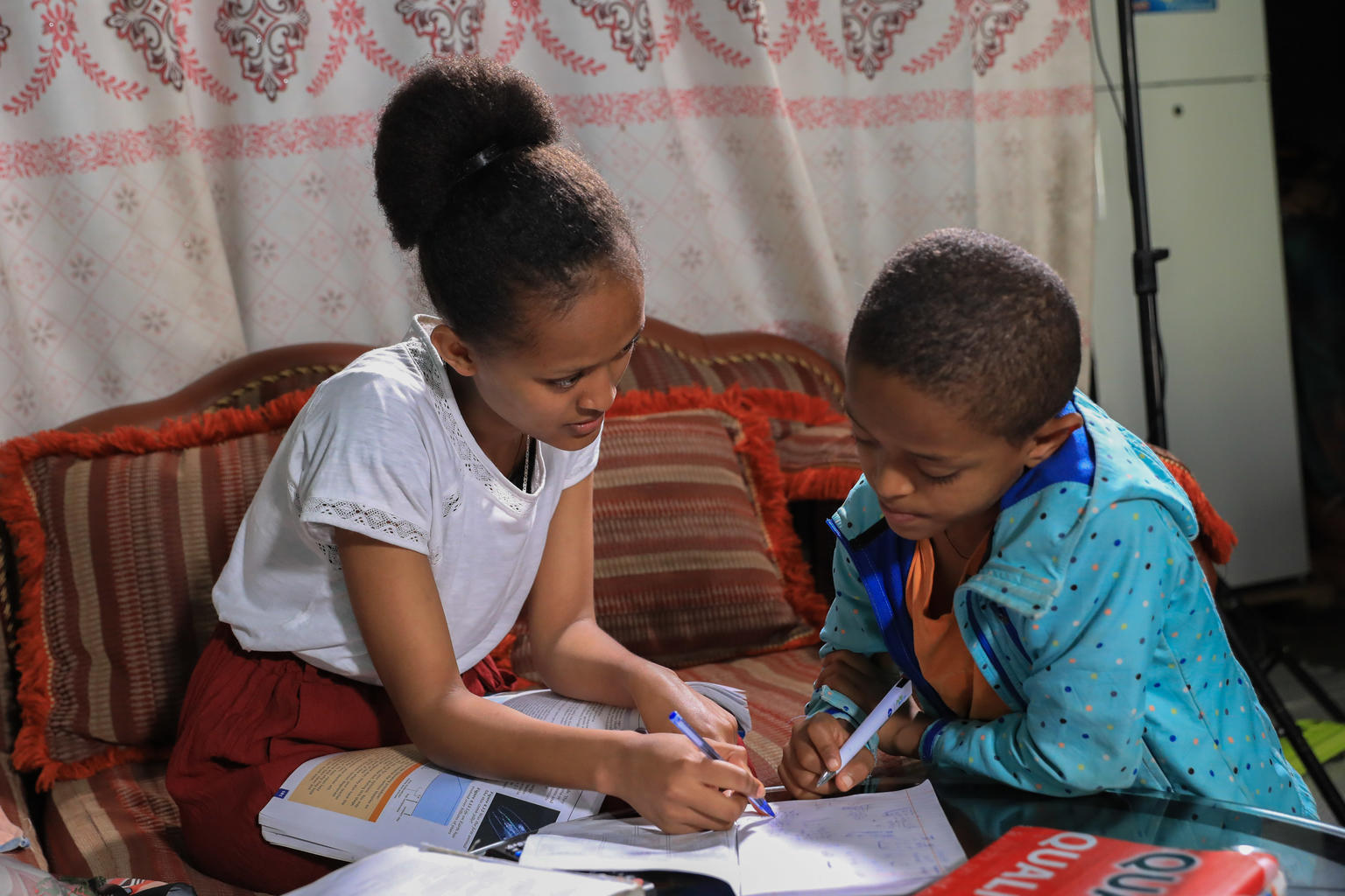 a sisters helps her younger brother with homework