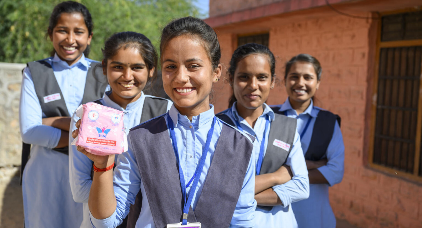 An adolescent girl holding menstrual pads at a school-based health education session.