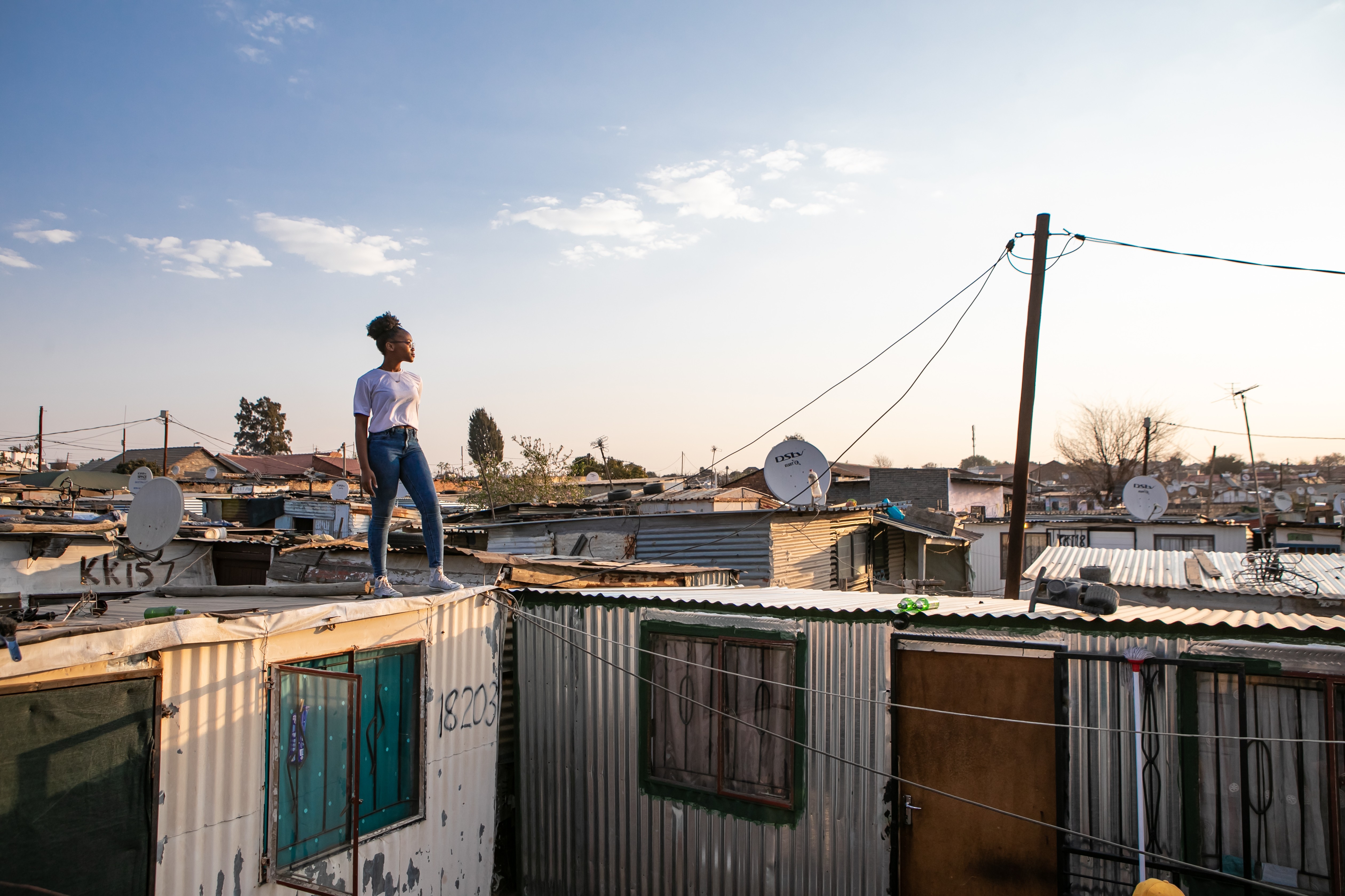 Adolescent girl standing on rooftop in informal settlement