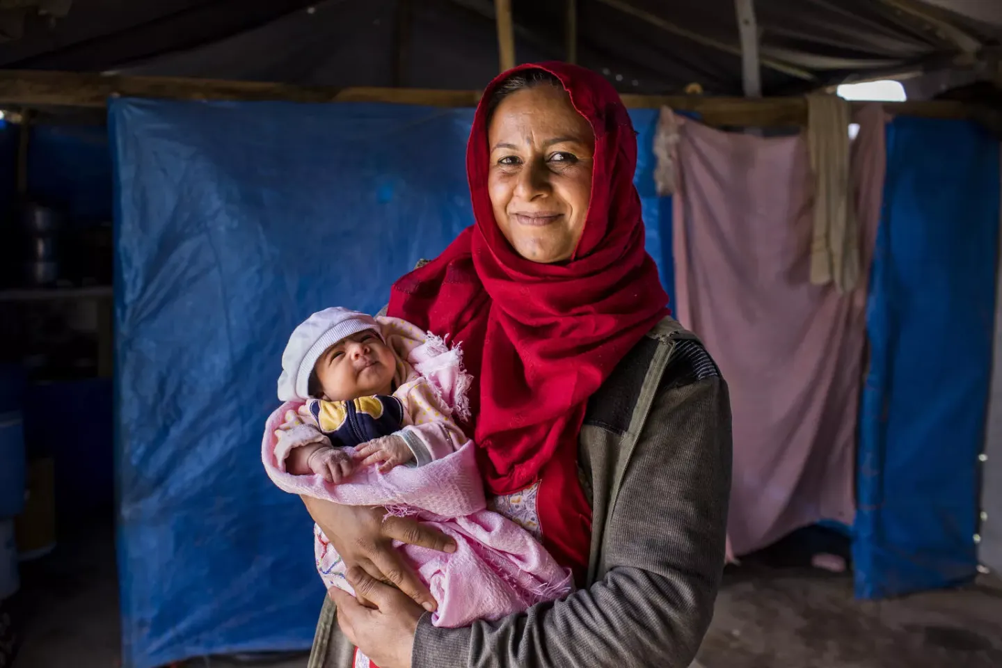 Iraq, Kawathar, 33, holds her newborn daughter Farah while the nurses from the mobile health team visit them in their home.