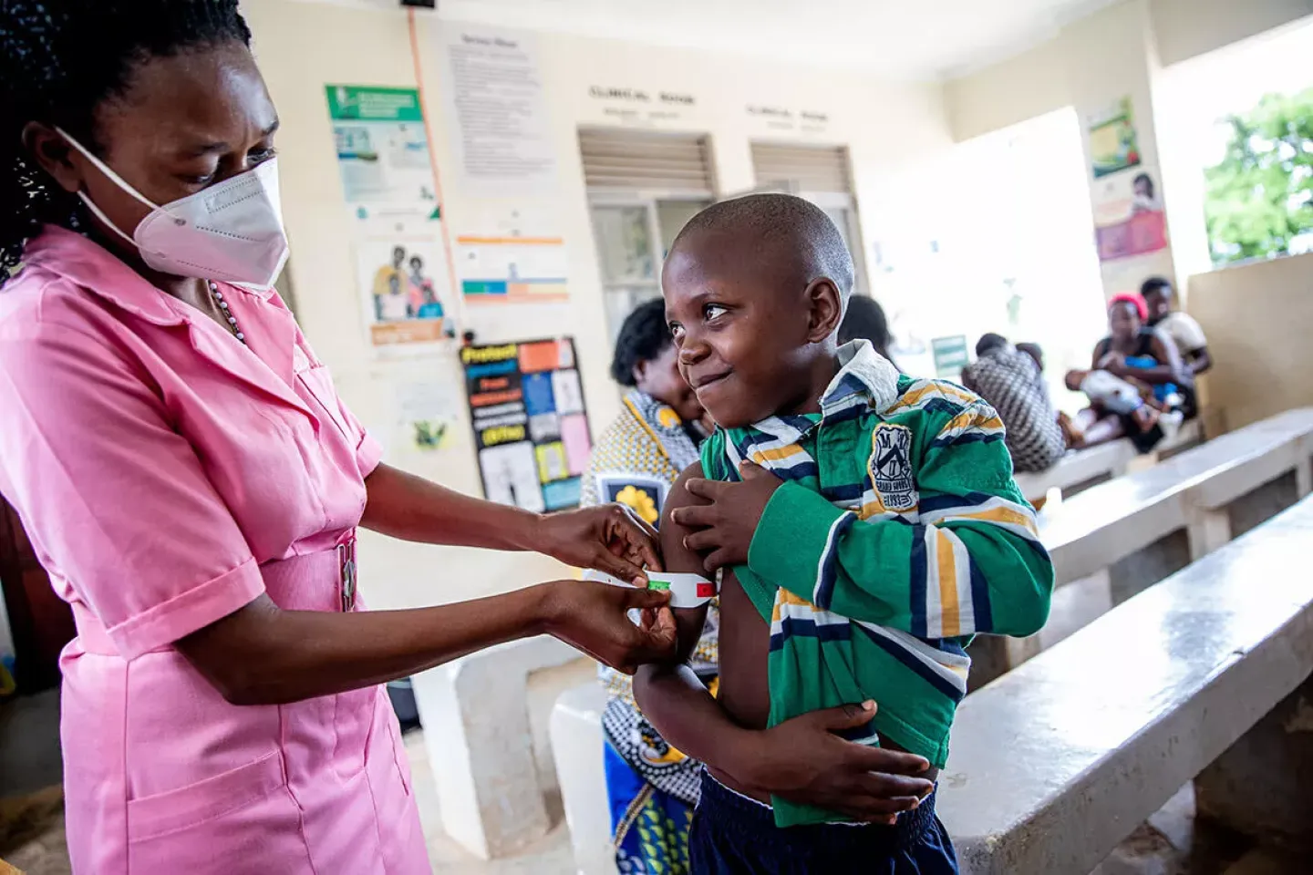 Margret and her son Ronald (9 yrs) attend a health screening at the Madudu Health Facility Mubende, Uganda. Ronald is weighed and his MUAC (measurement of upper arm circumference) is taken.