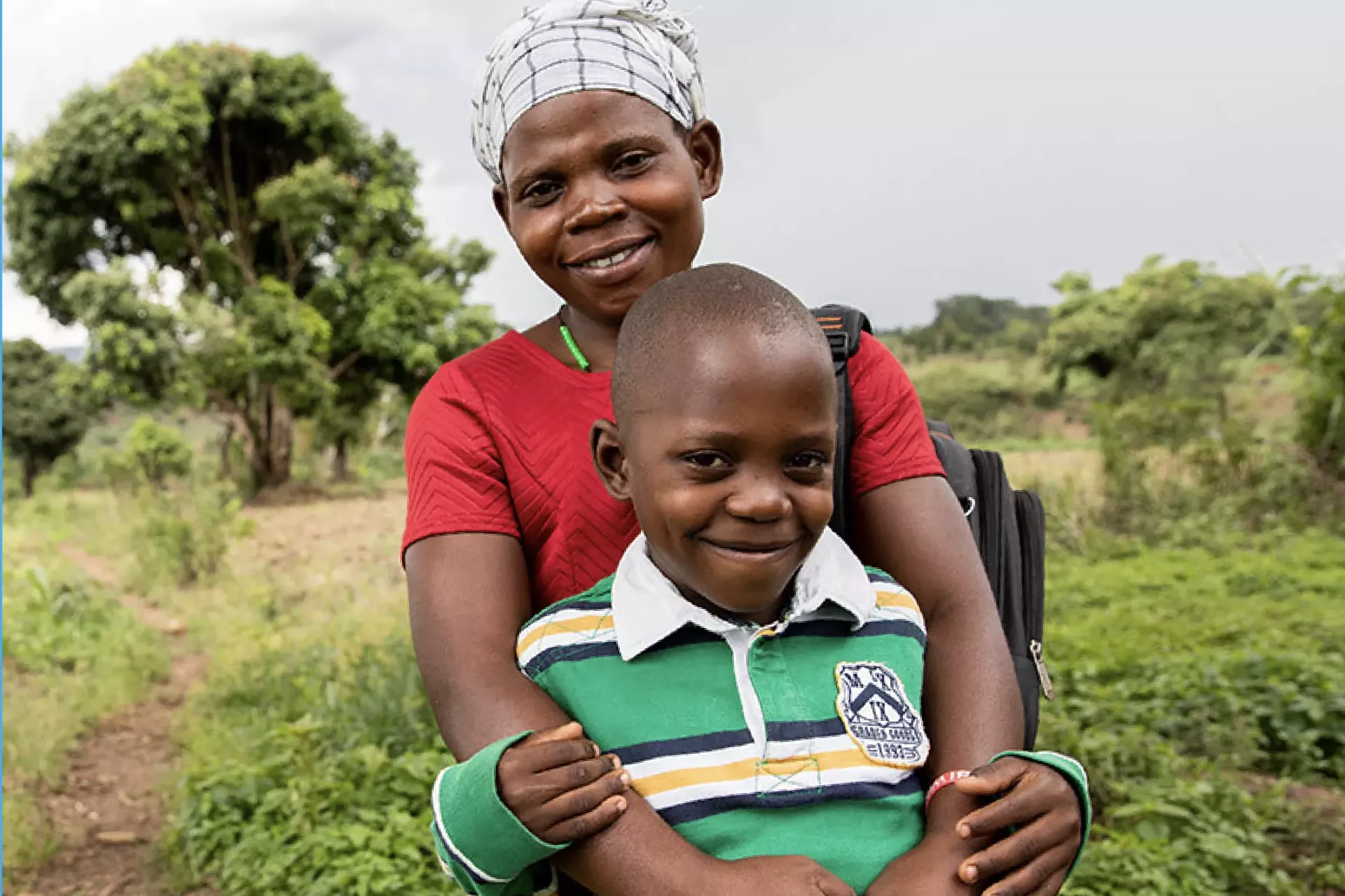 A smiling mother holds her son in front o her